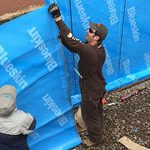 Aquatight crew installing foundation waterproofing on home